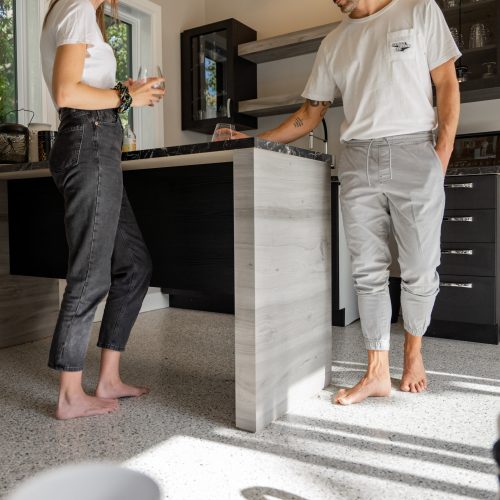 2022-10-06-betonsurface_photoshoot_editedhighresolution-27 alt="two person standing barefoot on a radiant kitchen floor made of polyaspartic"