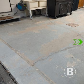 alt="Worn and stained concrete garage floor."
